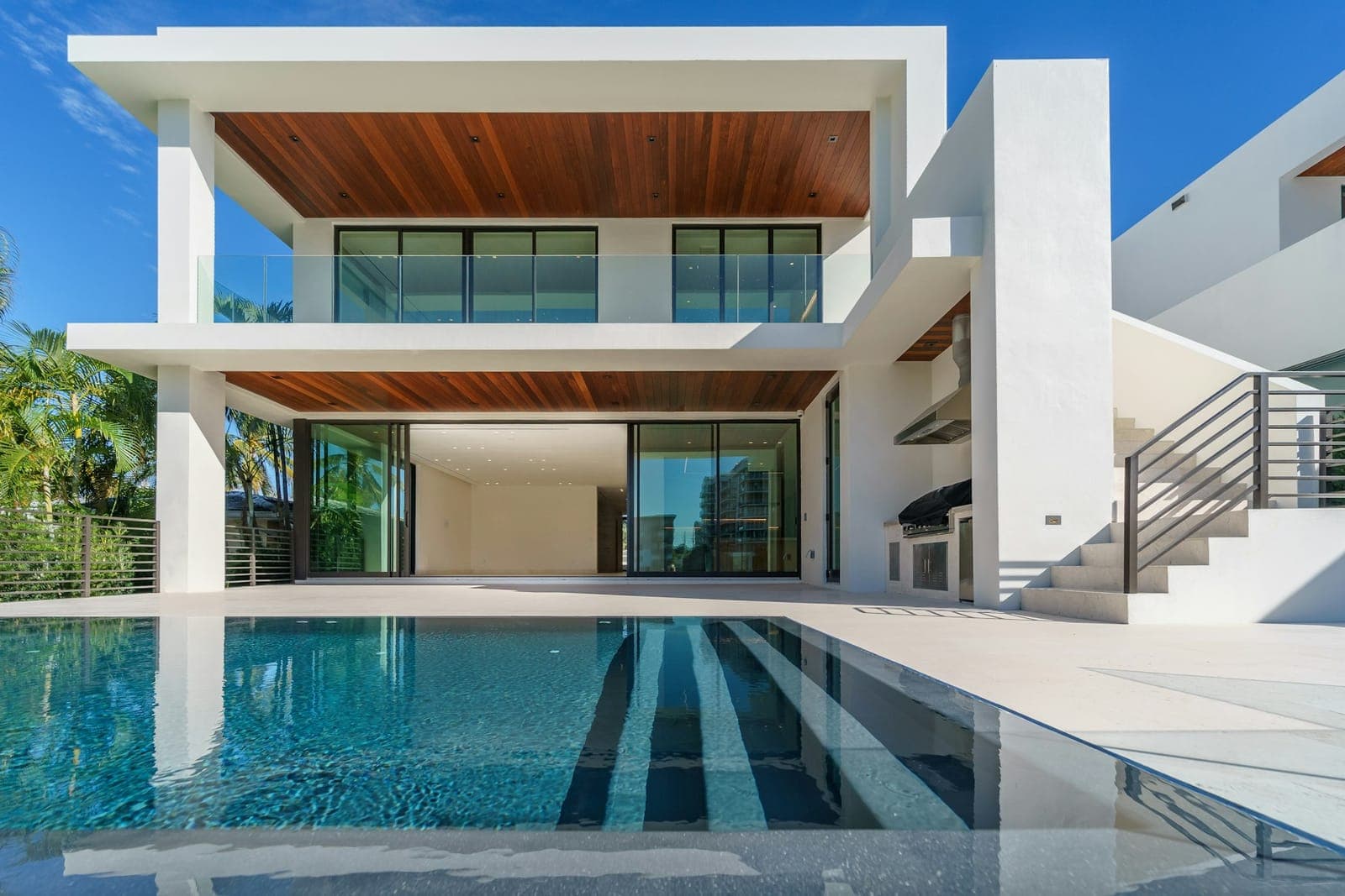 White luxury villa with timber soffit and a long reflecting pool
